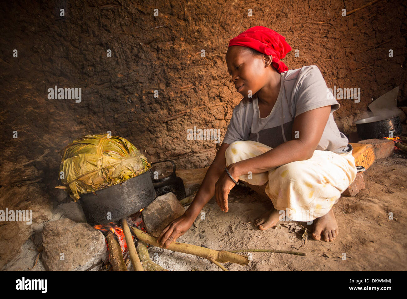 Woman cooking with banana leaves in kitchen - Gombe, Uganda, East Africa. Stock Photo