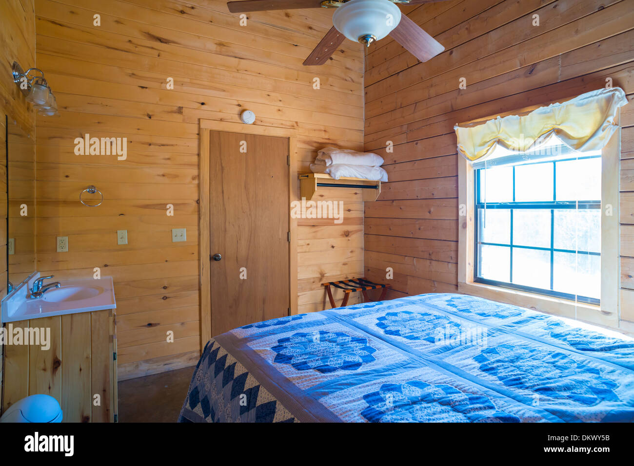 Simple bedroom interior with bed and vanity inside a log home cottage in Texas, USA. Stock Photo