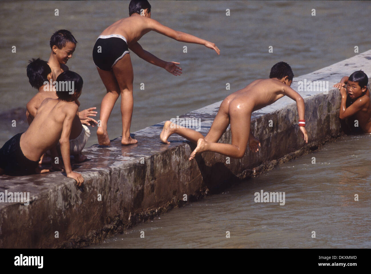 Boys and teenagers having fun in a river in the ancient town Feng Huang in Hunan Province of China Stock Photo