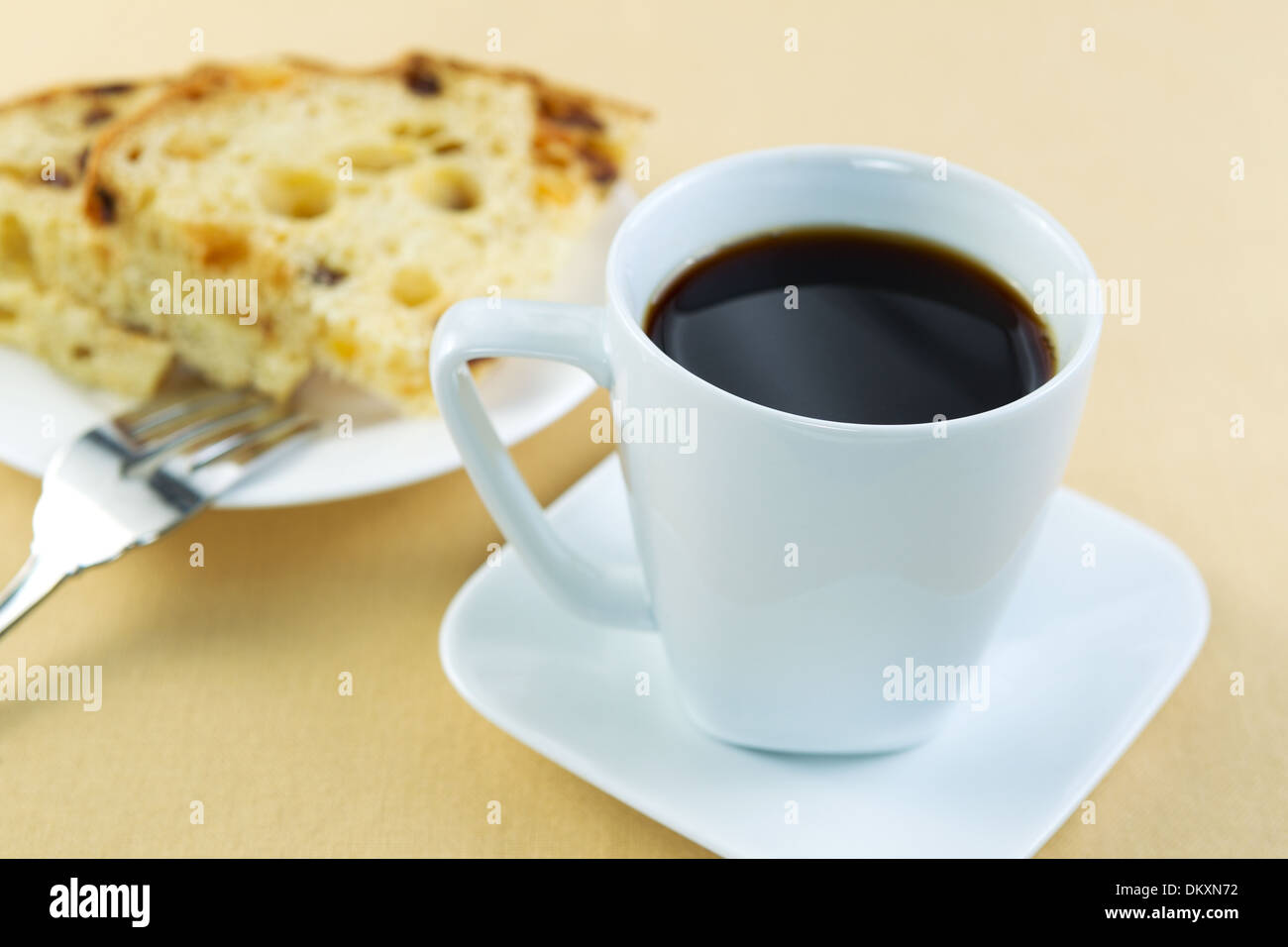 Horizontal photo of freshly brewed coffee, in white cup, with Italian cake slices on a white plate along with fork Stock Photo