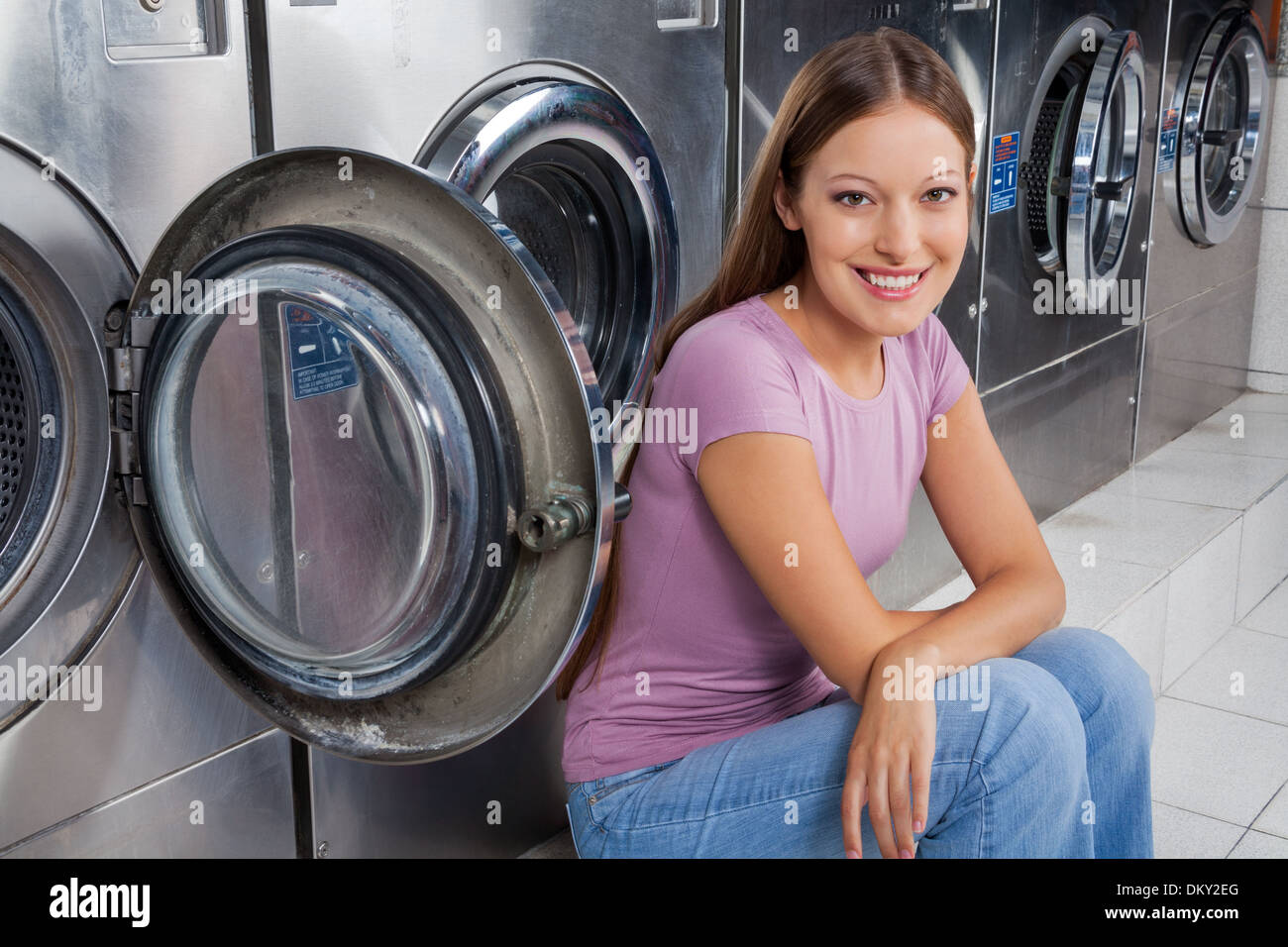 Woman Sitting Against Washing Machines Stock Photo