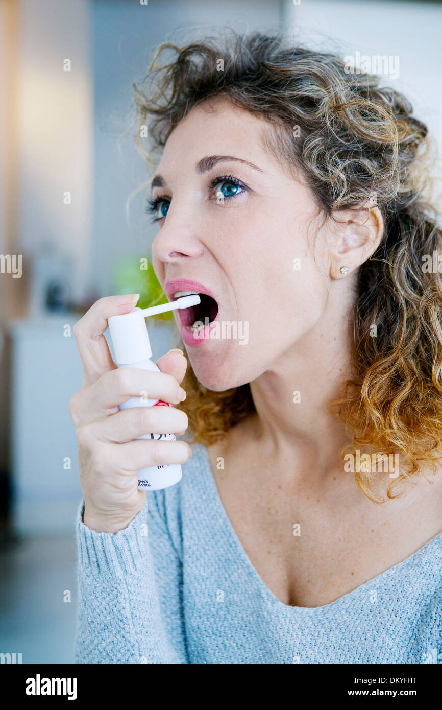 WOMAN USING SPRAY IN MOUTH Stock Photo