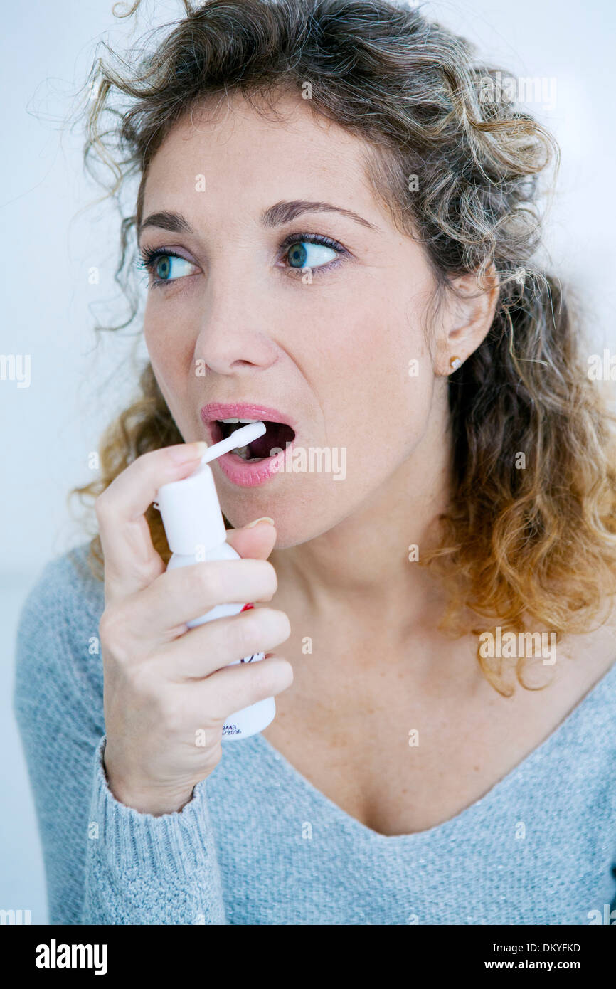 WOMAN USING SPRAY IN MOUTH Stock Photo