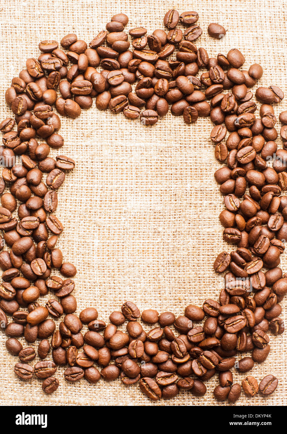 Spilled coffee beans frame over burlap textile Stock Photo