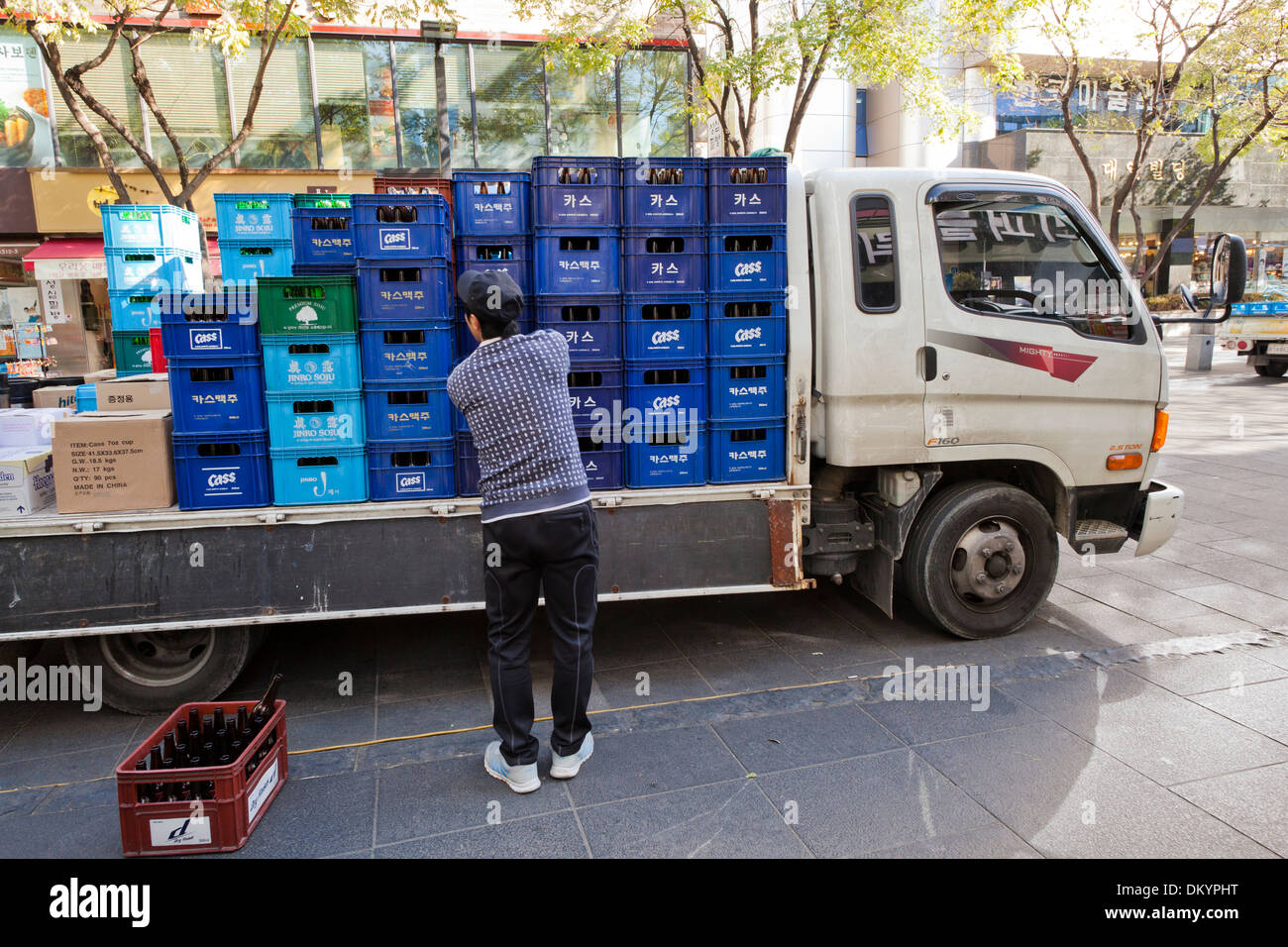 Man stacking beer cases on delivery truck - Seoul, South Korea Stock Photo