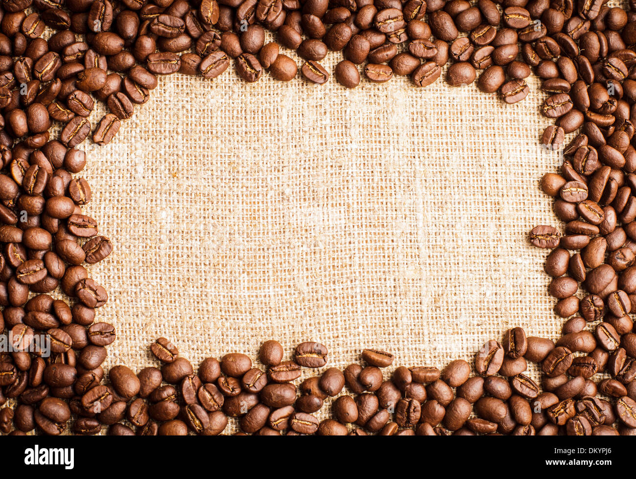 Spilled coffee beans frame over burlap textile Stock Photo