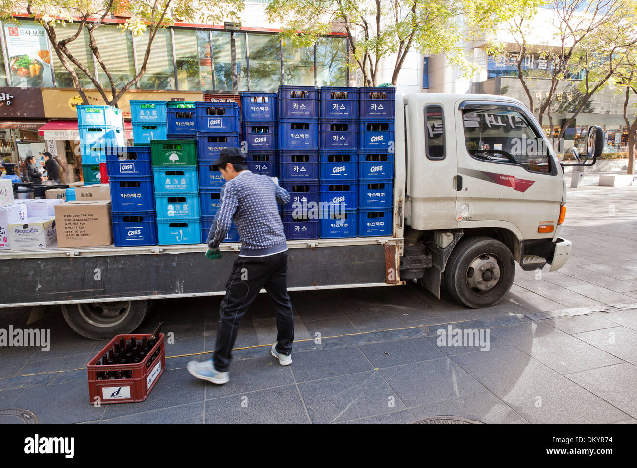 Man stacking beer cases on delivery truck - Seoul, South Korea Stock Photo