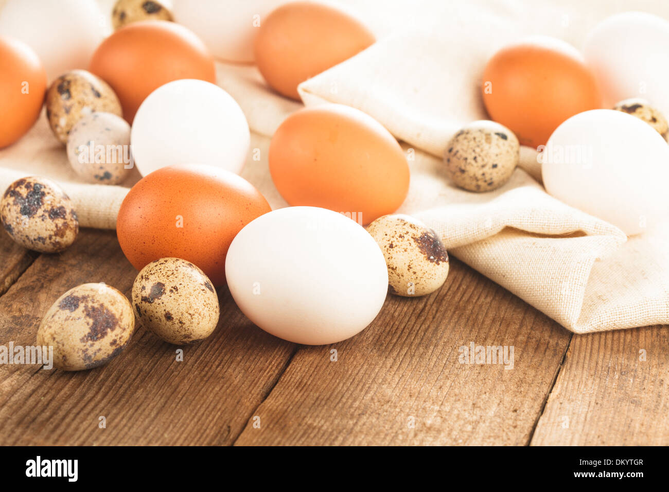 Eggs on textile tablecloth over rustic wooden table Stock Photo