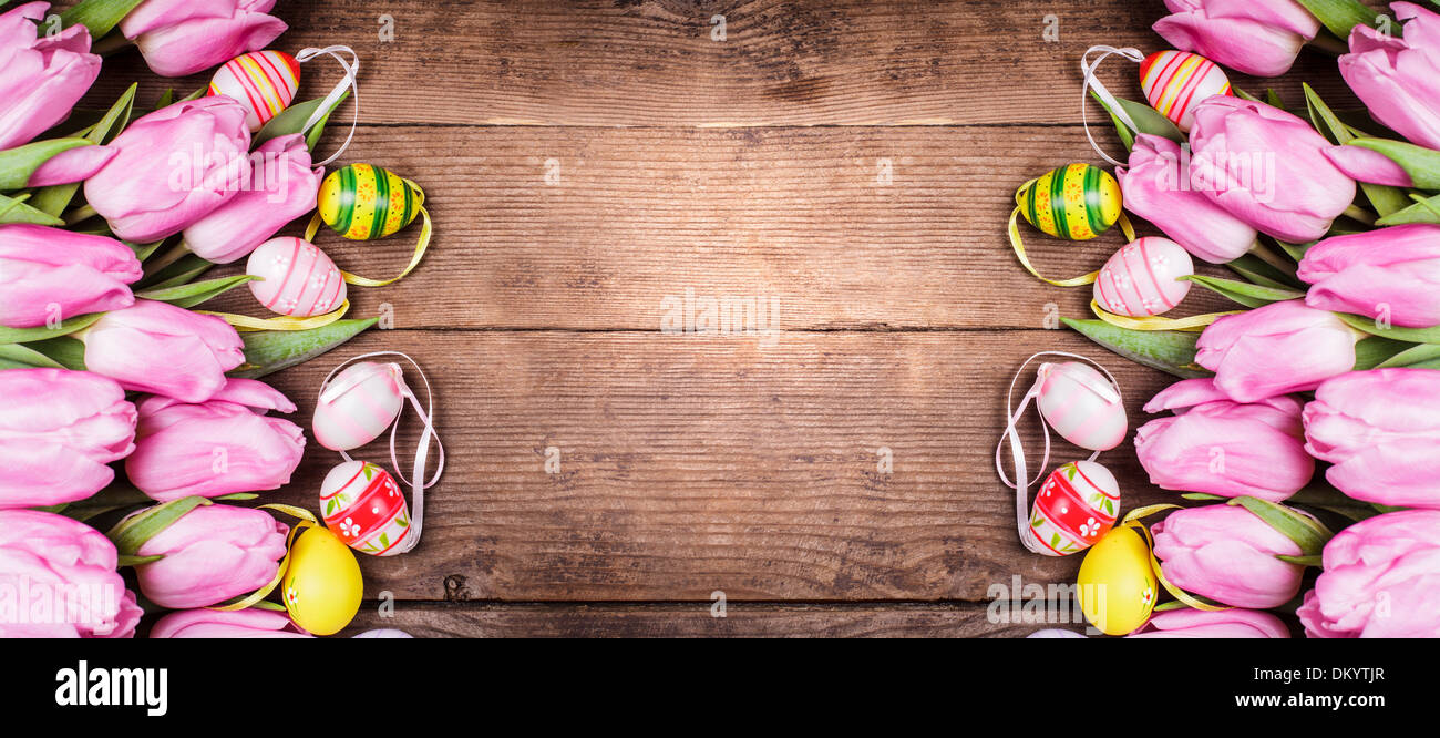 Tulips and eggs border over wooden backdrop. Easter decorations Stock ...