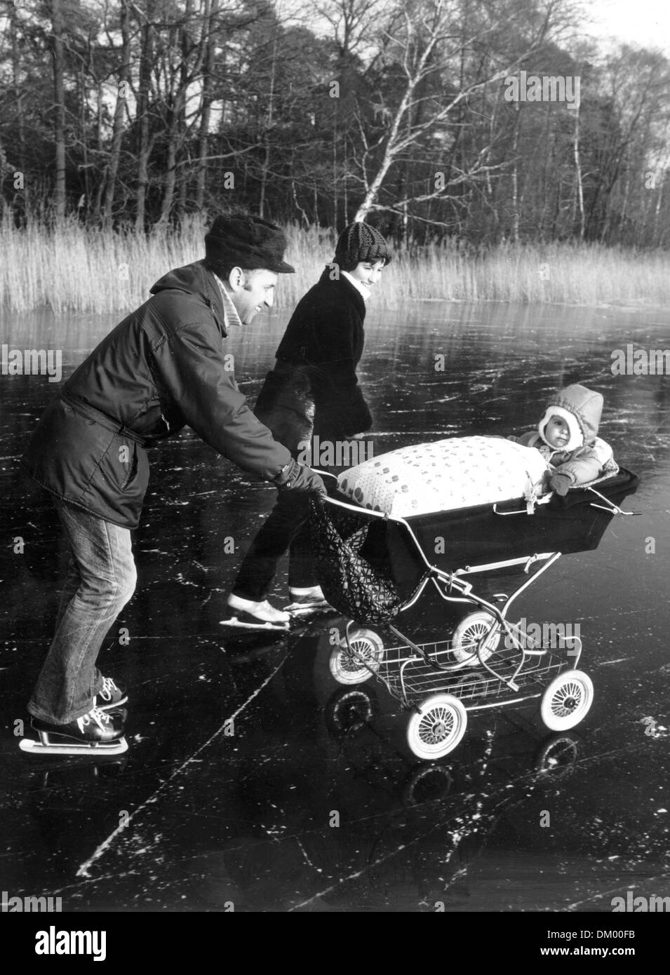 View of parents on ice skates with their child in the baby carriage on the Motzen Lake in the south of Berlin, Germany, in February 1984. Photo: Manfred Uhlenhut Stock Photo