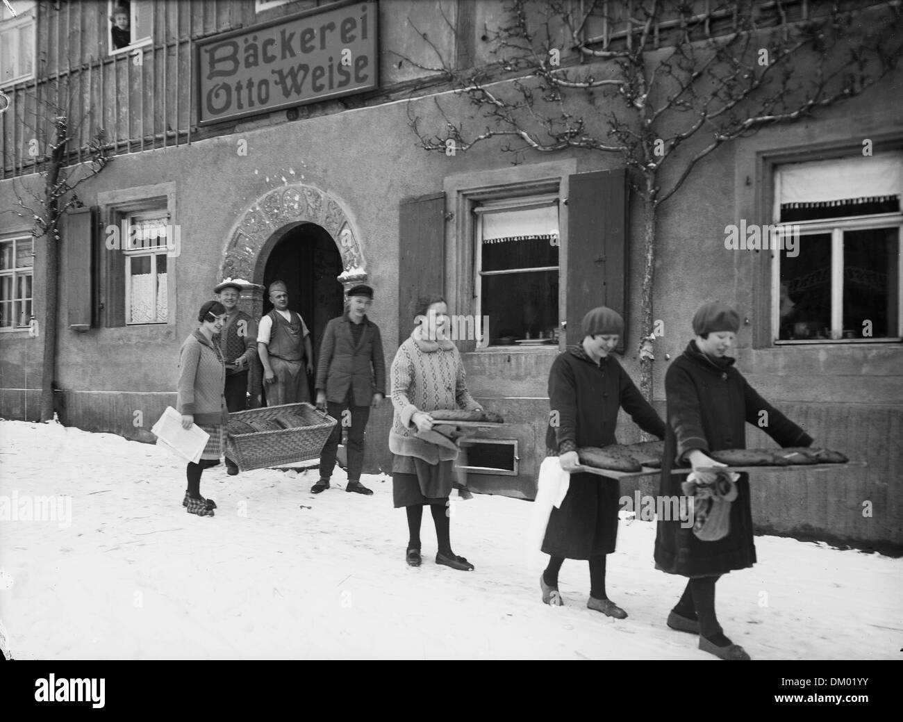 Women carry trays and a basket with stollen from the bakery Otto Weise at the market in Kohren-Salis, Germany. During Christmas time, it used to be normal for families to bring the ingredients into a bakery to have the great number of Christmas stollen baked in the big oven of the bakery. Photo: Deutsche Fotothek/Johannes Müller Stock Photo