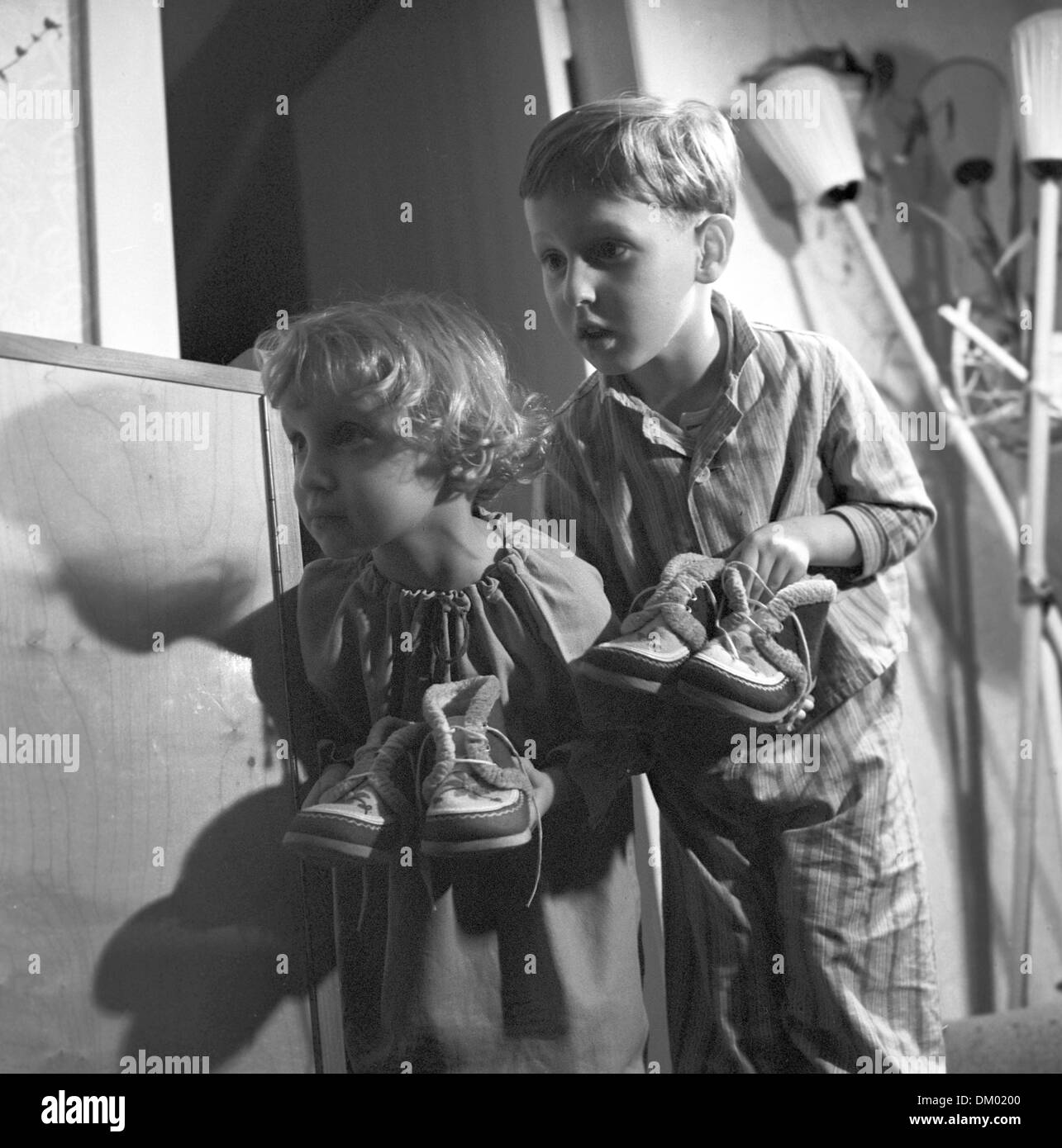 A small girl and a small boy in the pajamas carry their shoes to the door for Saint Nicholas, undated photograph (December 1963). Photo: Heinz Junge Stock Photo