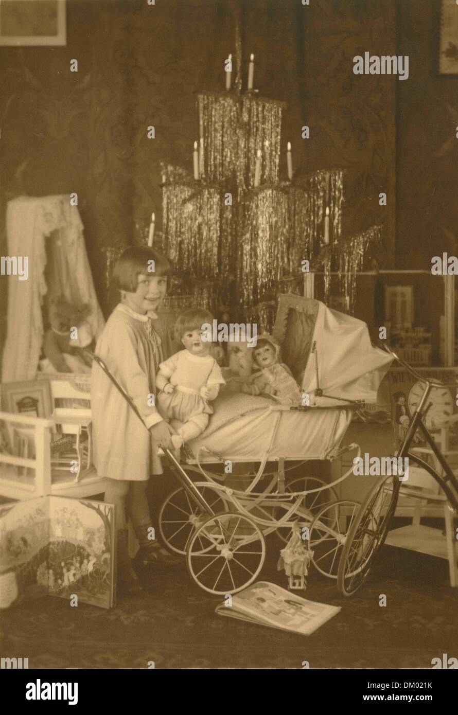 A girl is pictured with a doll pram and presents in front of Christmas tree decorated with lametta, undated photograph (around 1927). Photo: Deutsche Fotothek/Berger Stock Photo