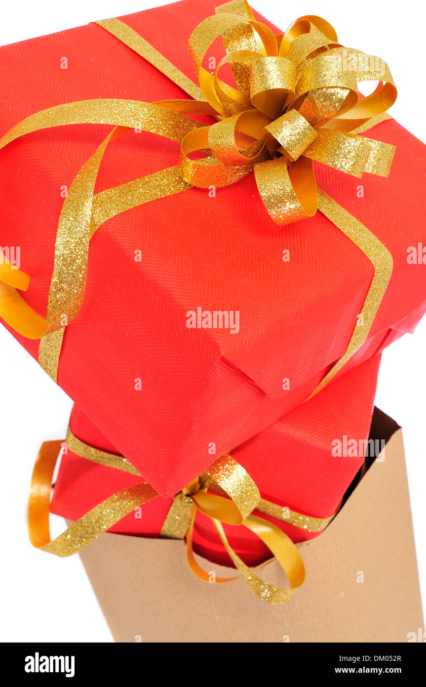 some gifts wrapped with red wrapping paper and with a golden ribbon, in a shopping bag on a white background Stock Photo
