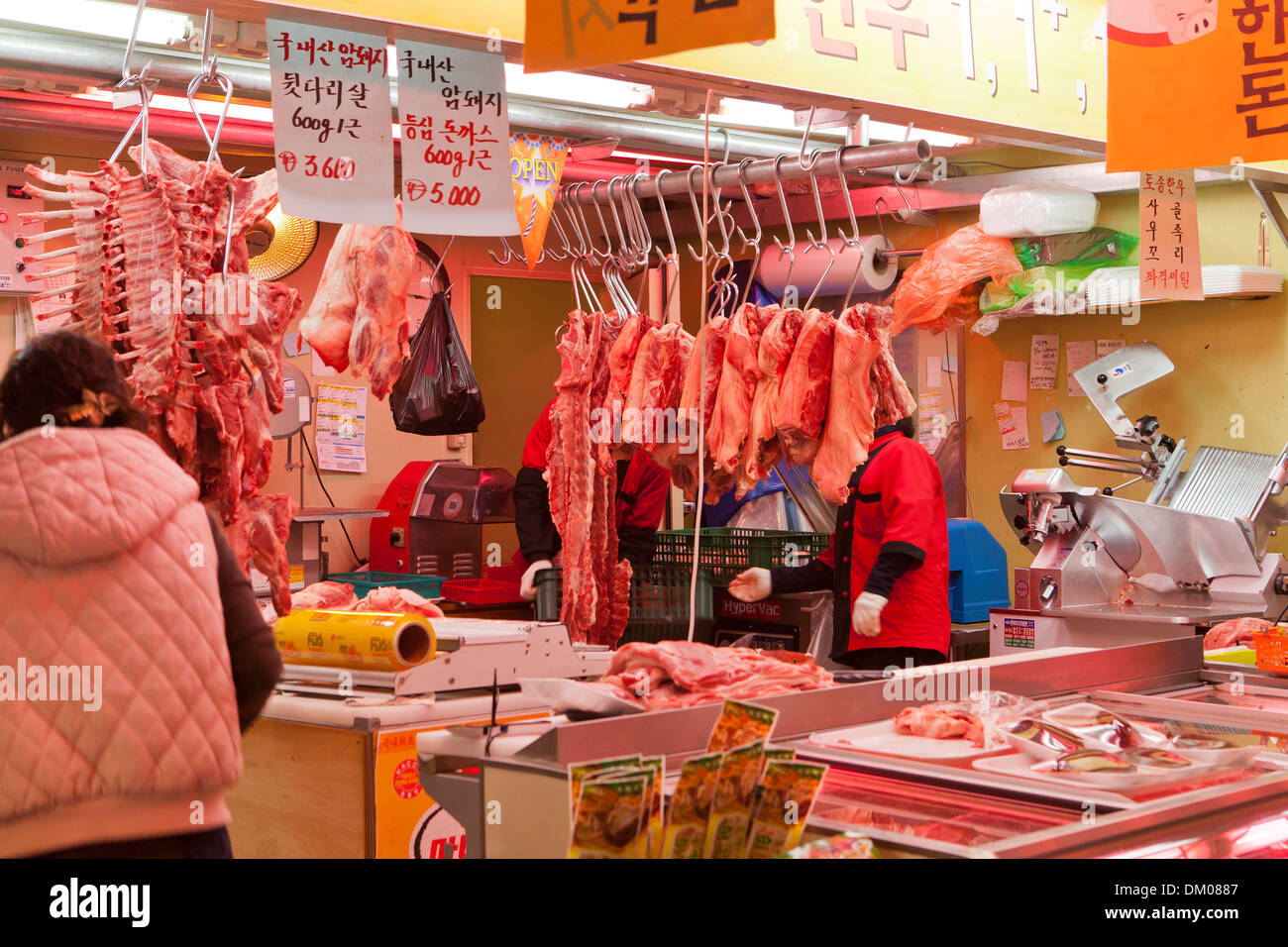 Cuts of meat hanging on hooks at a traditional market butcher shop - Seoul, South Korea Stock Photo