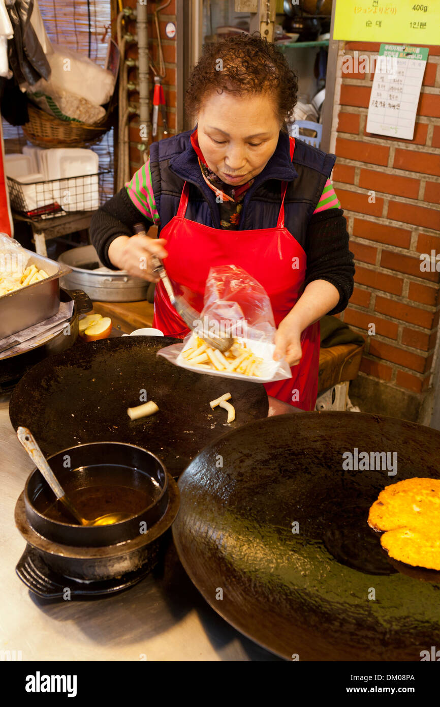 Woman making Tteokbokki (topokki) at traditional market - Seoul, South Korea Stock Photo