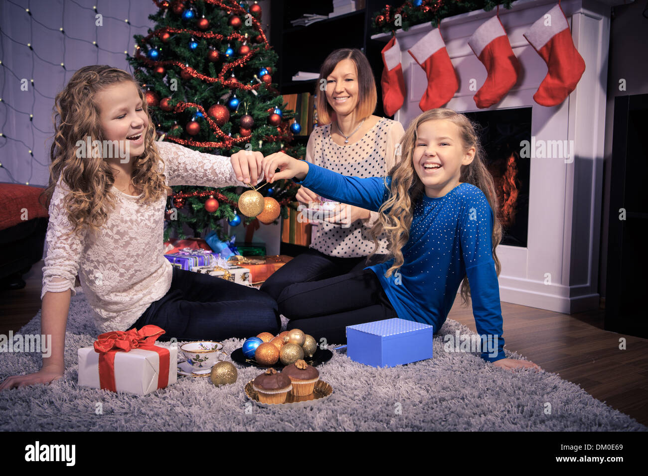 two teenage sisters and mother decorating a Christmas tree Stock Photo
