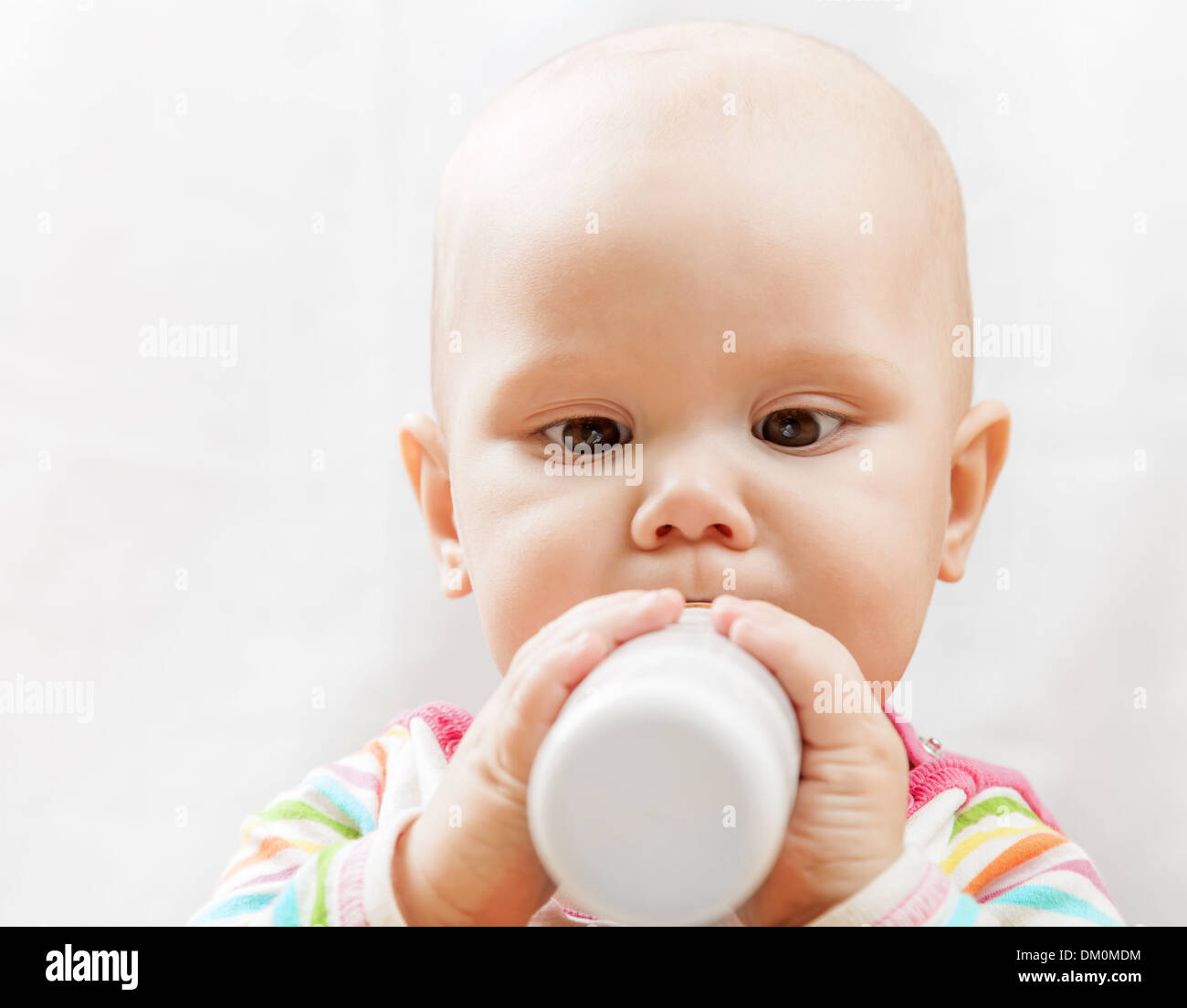 Little brown eyed Caucasian baby with bottle of milk Stock Photo