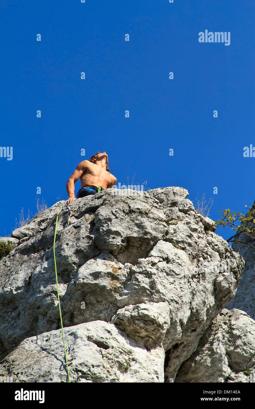 Rock climber celebrating on a top of limestone cliff after successful