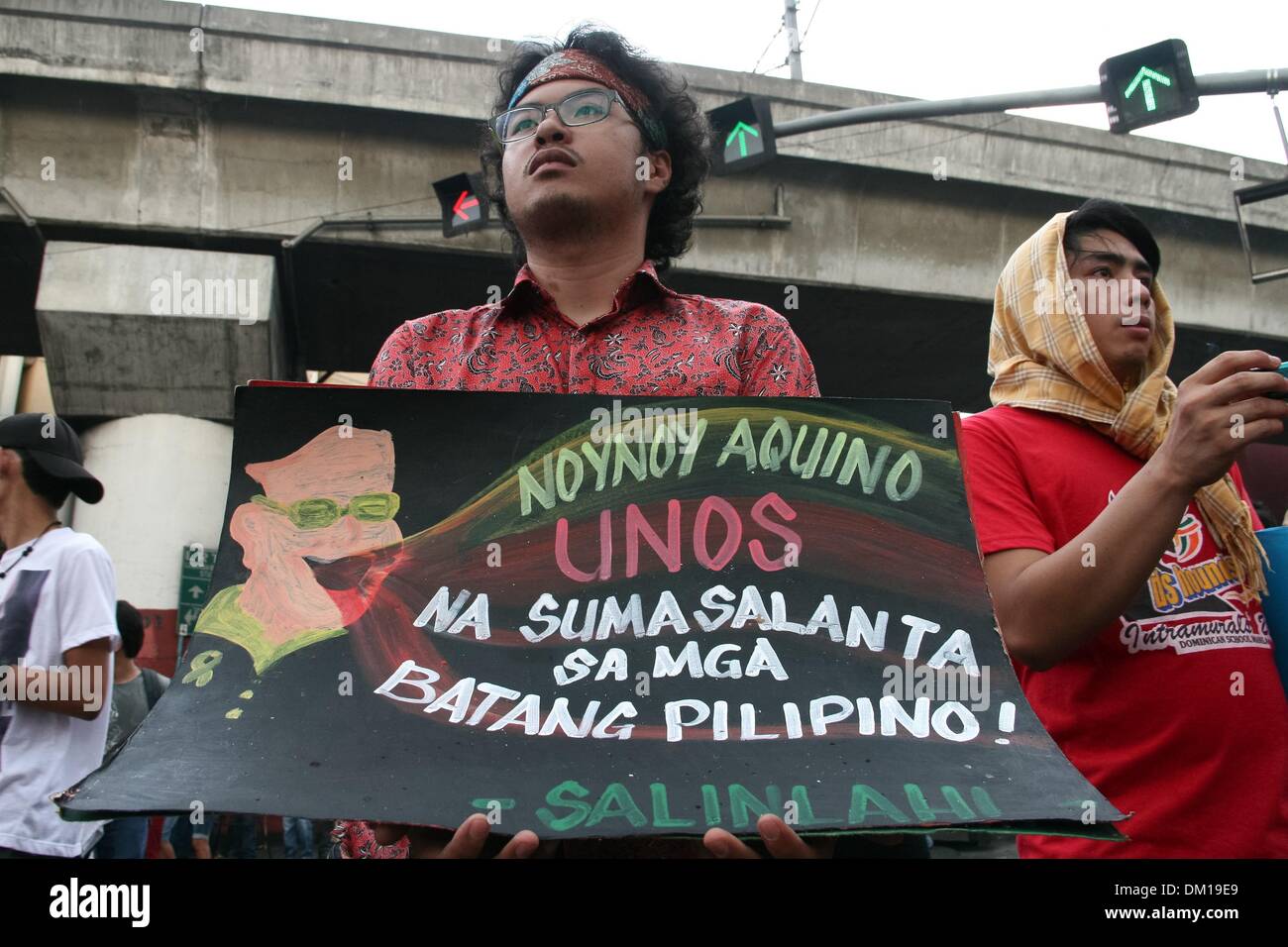 Manila, Philippines. 10th Dec, 2013. A protester holding a poster in Mendiola, Manila comparing President Aquino III to a typhoon that destroyed the Filipino youth. -- Protesters commemorated the International Human Rights Day with a march to Mendiola, Manila bringing effigies of President Aquino III. They dubbed Aquino as the ''impunity king'' for alleged human rights violations since he started his term.Photo: J Gerard Seguia/NurPhoto Credit:  J Gerard Seguia/NurPhoto/ZUMAPRESS.com/Alamy Live News Stock Photo