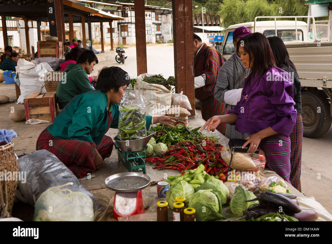 Bhutan, Bumthang Valley, Chamkhar town bazaar, woman in kira and toego buying chillies Stock Photo