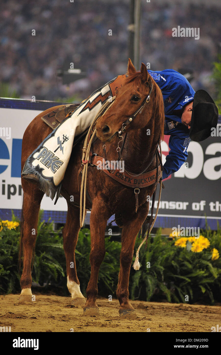 A pick up man adjusts the cinch on his saddle during the PBR Built Ford