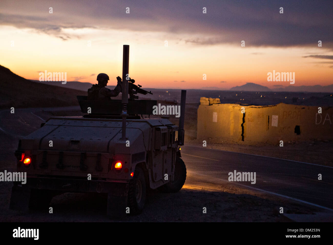 A US Marine provides security from a humvee during a convoy outside Forward Operating Base Zeebrugge at dusk December 1, 2013 in Kajaki district, Helmand province, Afghanistan. Stock Photo