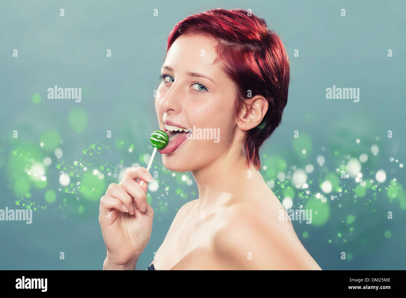redhead woman licking a green lollipop Stock Photo