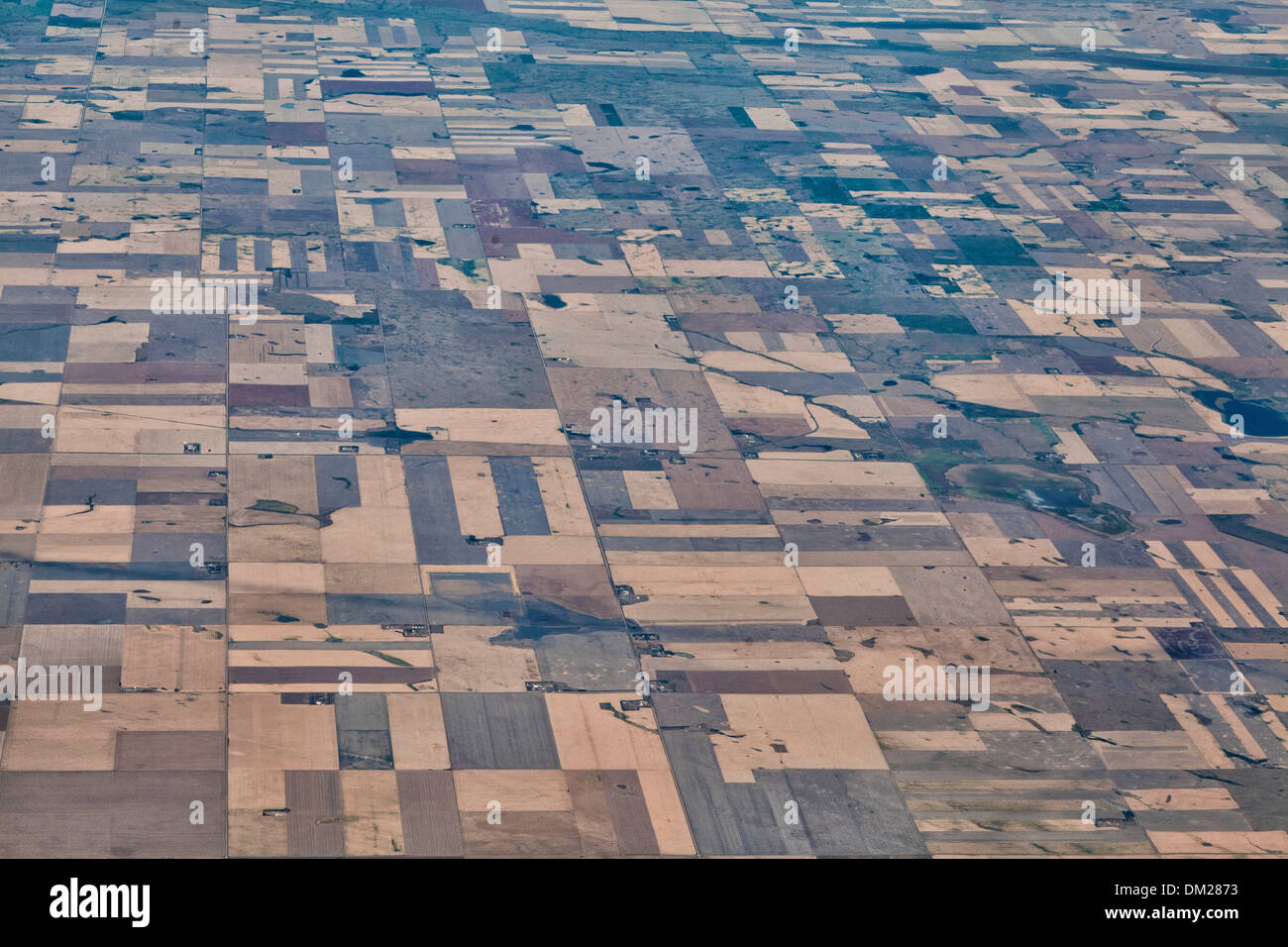 A look at the patchwork pattern of the Canadian Prairie fields from an airplane window in the sky Stock Photo