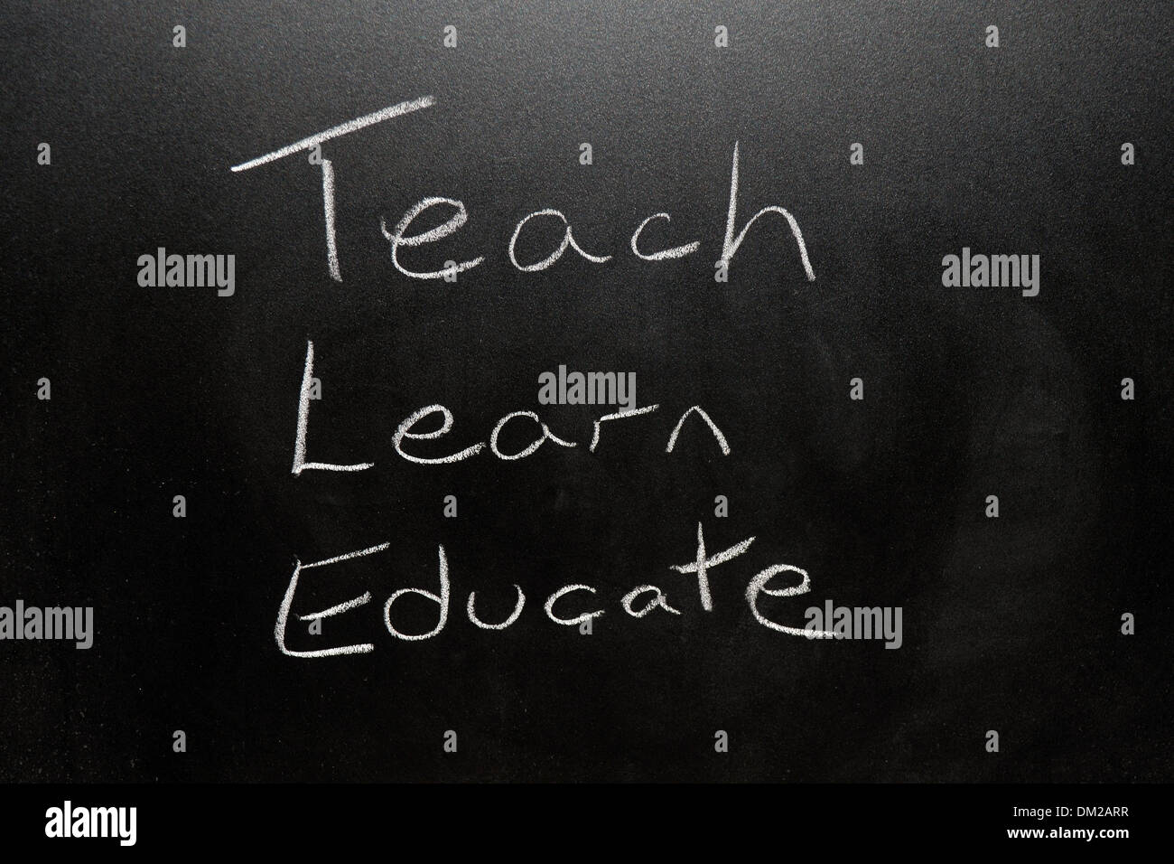 Close up of a blackboard with Teach, Learn, Educate written on it in chalk. Stock Photo