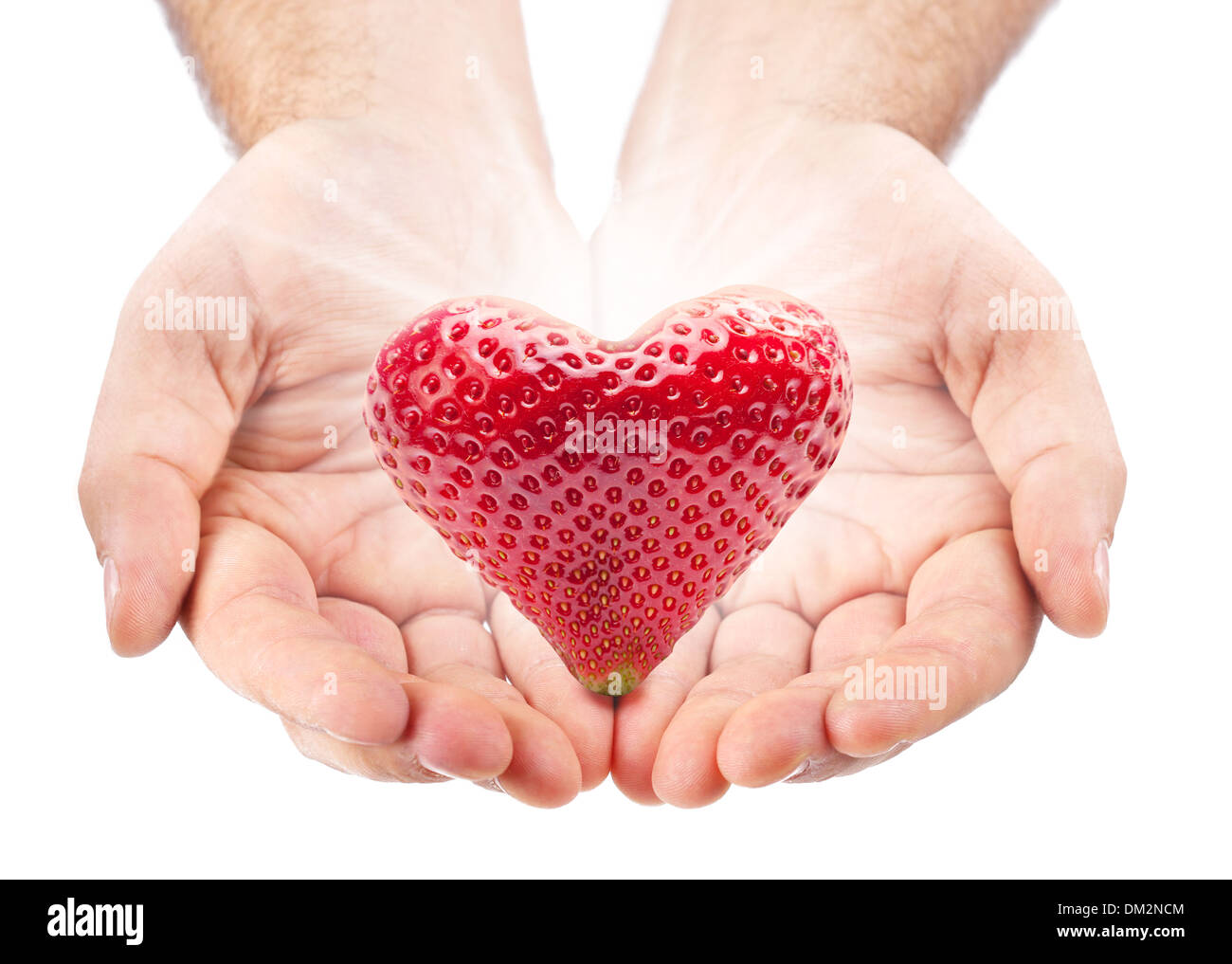 Strawberry in the shape of heart in male hands. Stock Photo