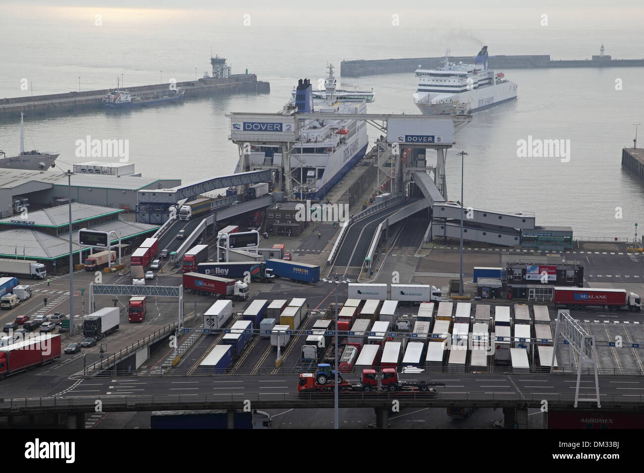 Ferries dock at the port of Dover, Kent, UK. Lorries are shown leaving one ferry as another maneuvers in the harbour Stock Photo