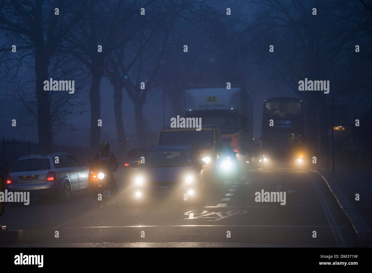 Commuter traffic and pedestrians at dawn on a foggy morning in south London. Stock Photo