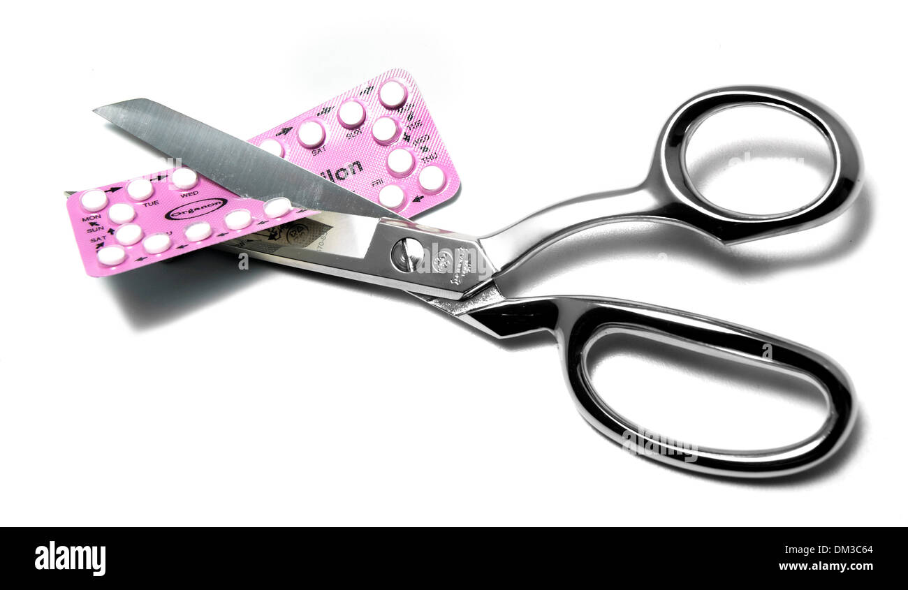 Scissors cutting birth control pill packet cut out on white background Stock Photo