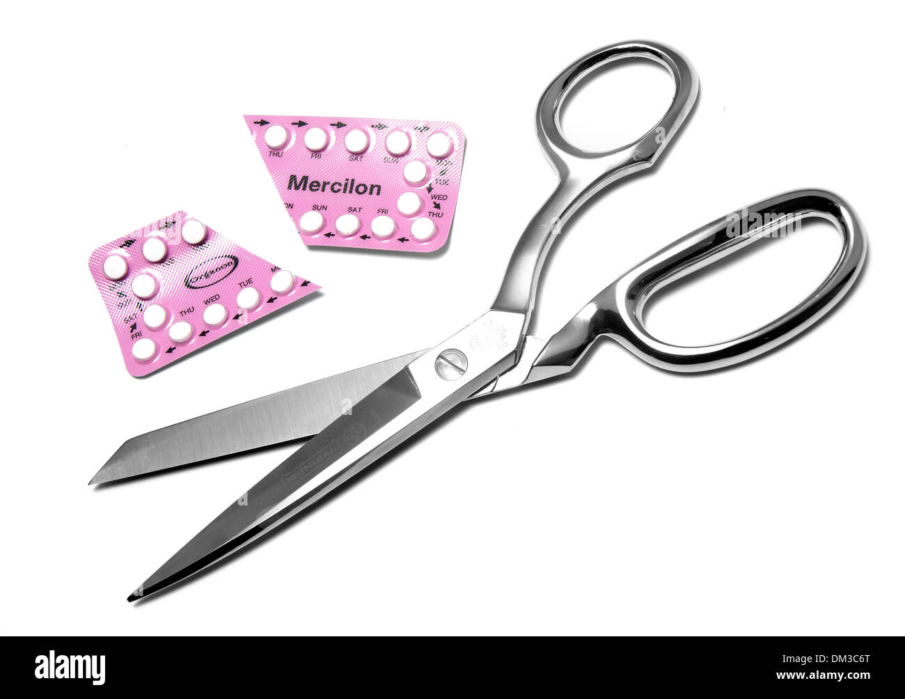 Scissors cutting birth control pill packet cut out on white background Stock Photo