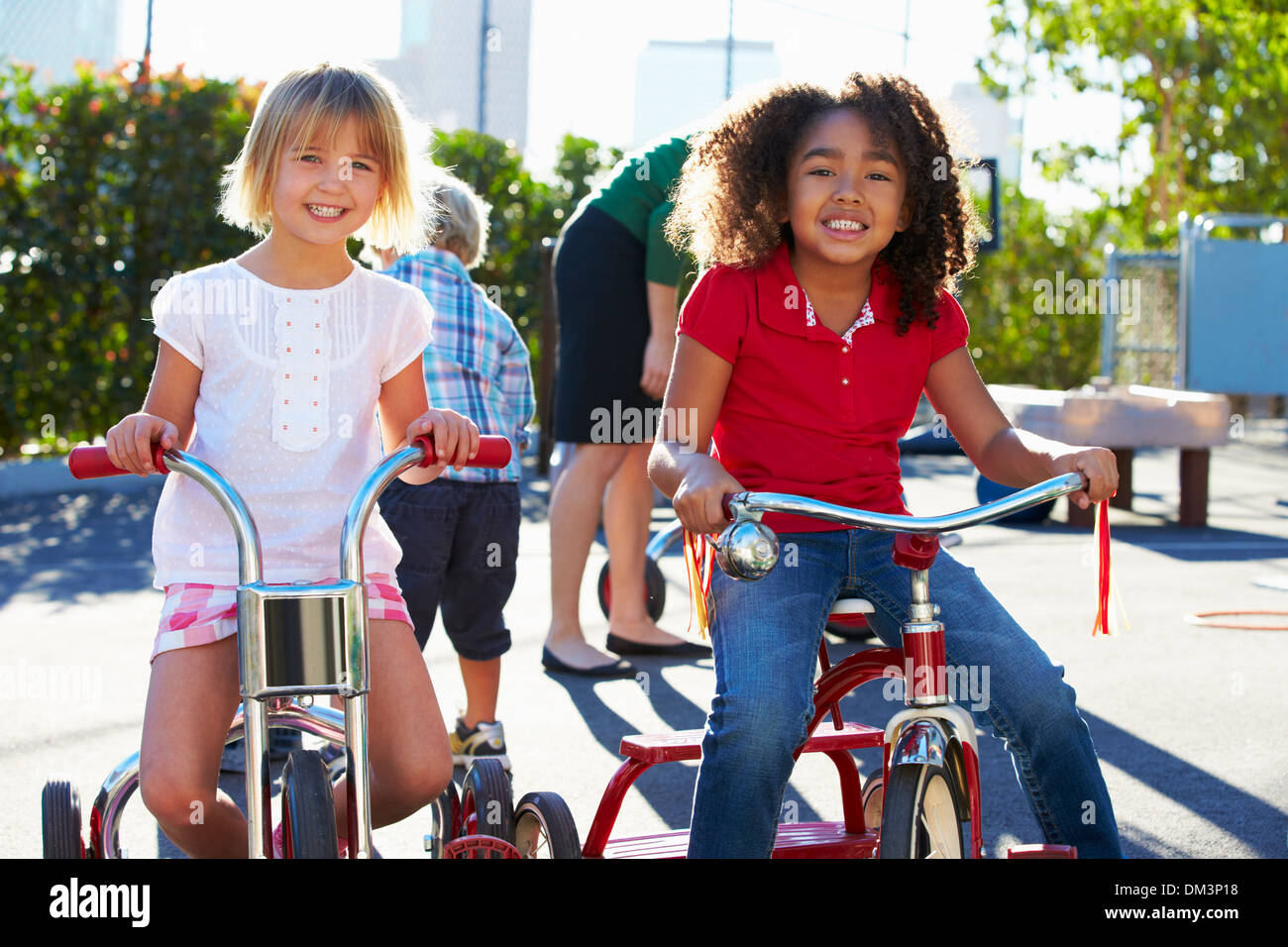 Two Girls Riding Tricycles In Playground Stock Photo Alamy