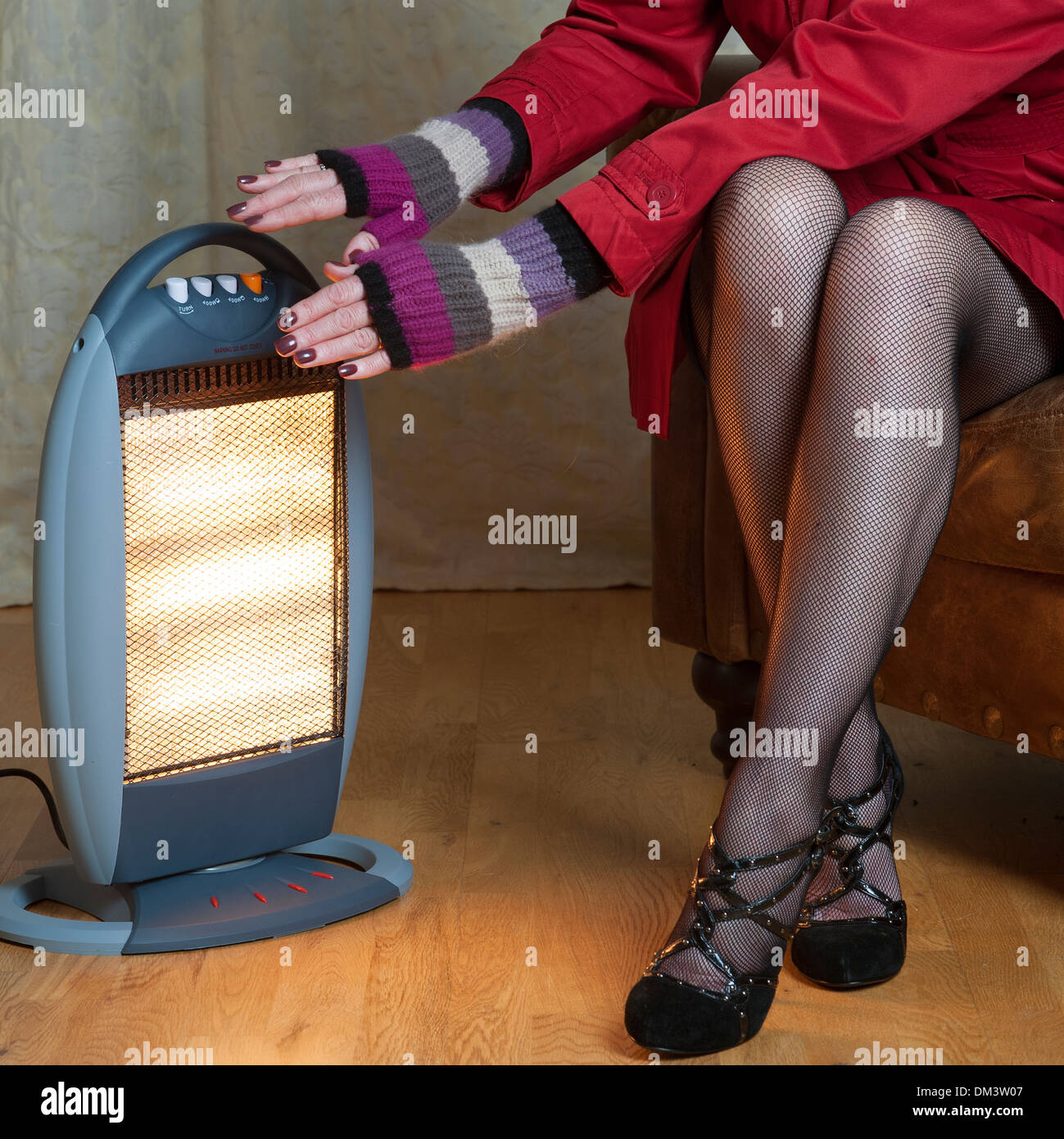 Woman keeping warm with an electric fire Stock Photo
