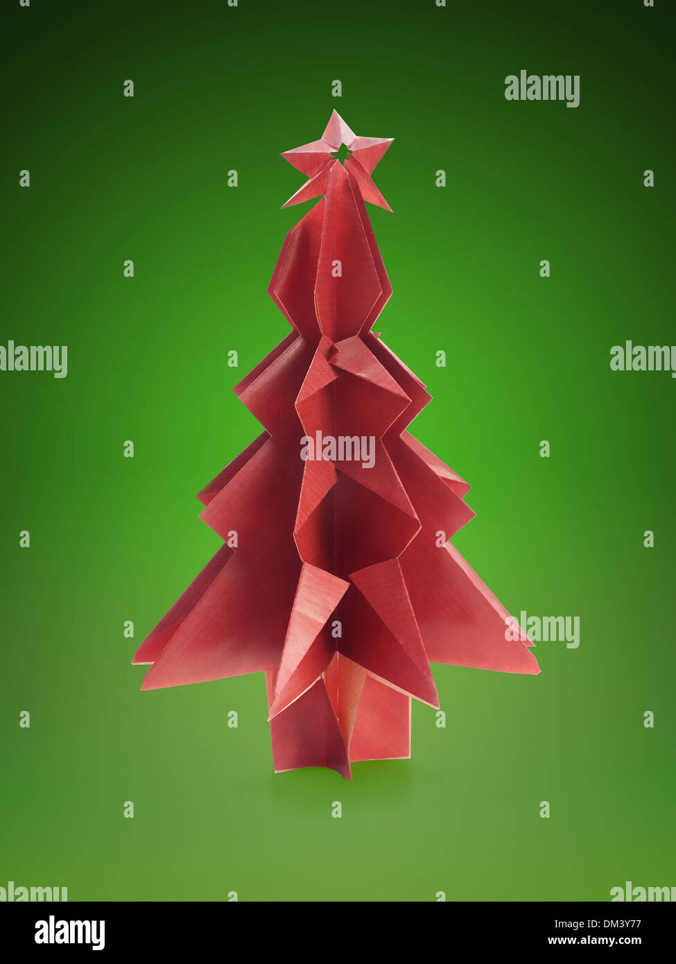 Origami christmas tree made from red paper shot over green background ...