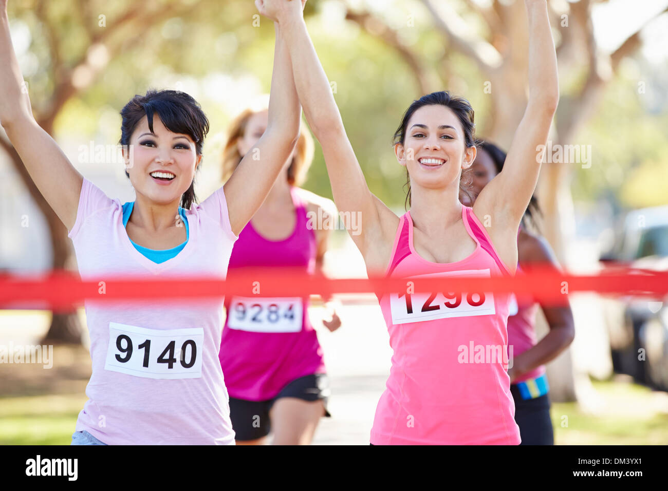 Two Female Runners Finishing Race Together Stock Photo