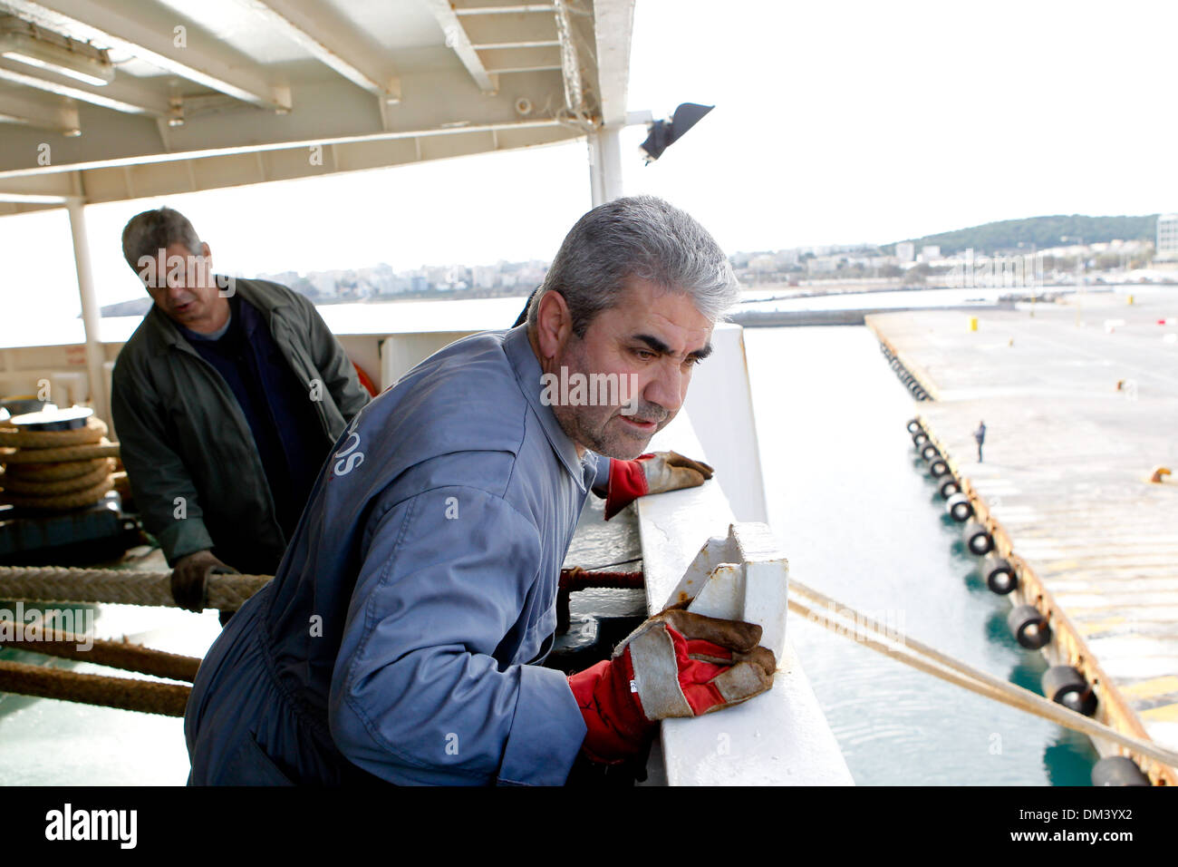 Ship crew guiding heavy duty mooring rope during docking procedure ...