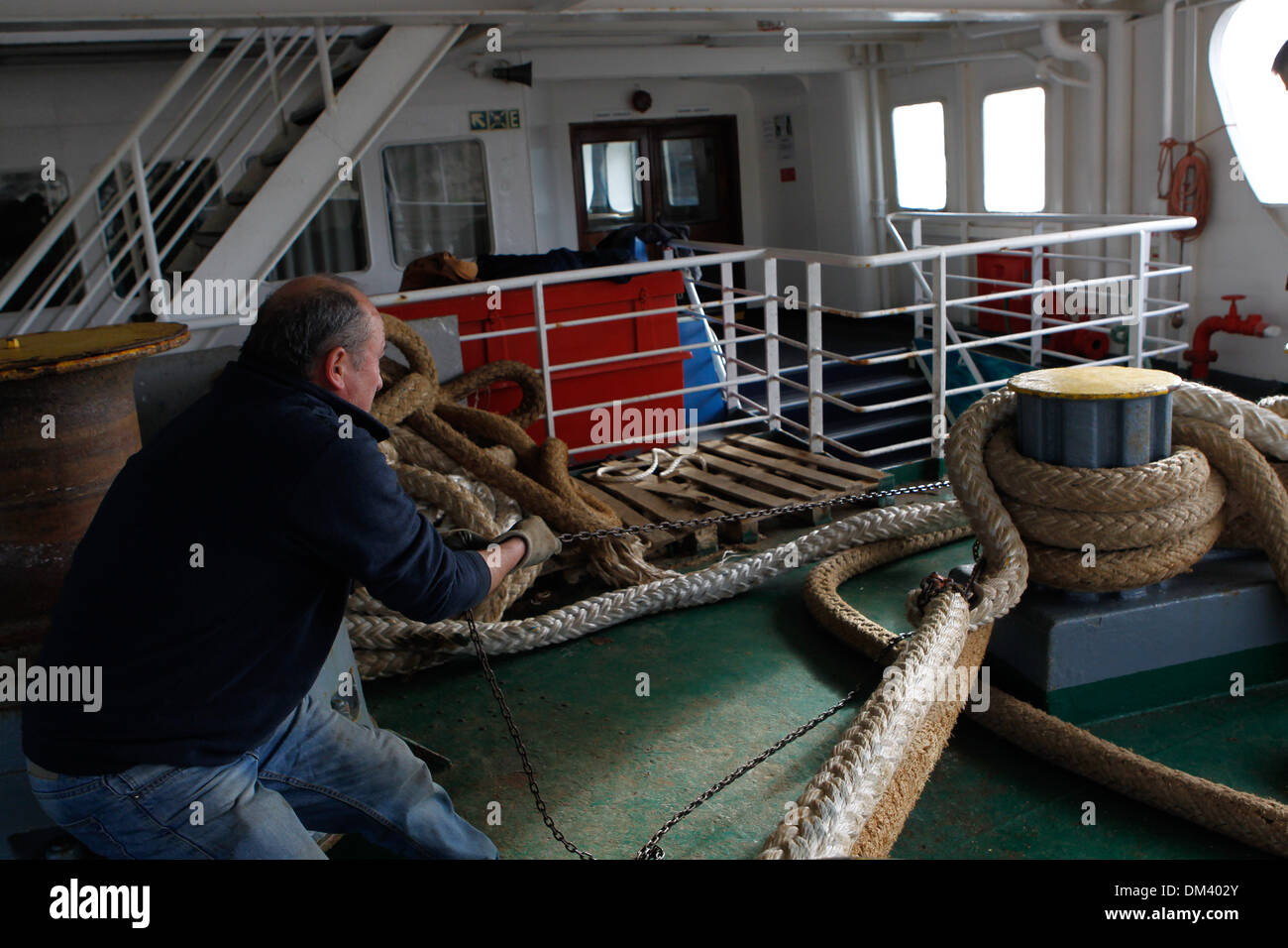 Ship crew guiding heavy duty mooring rope during docking procedure ...
