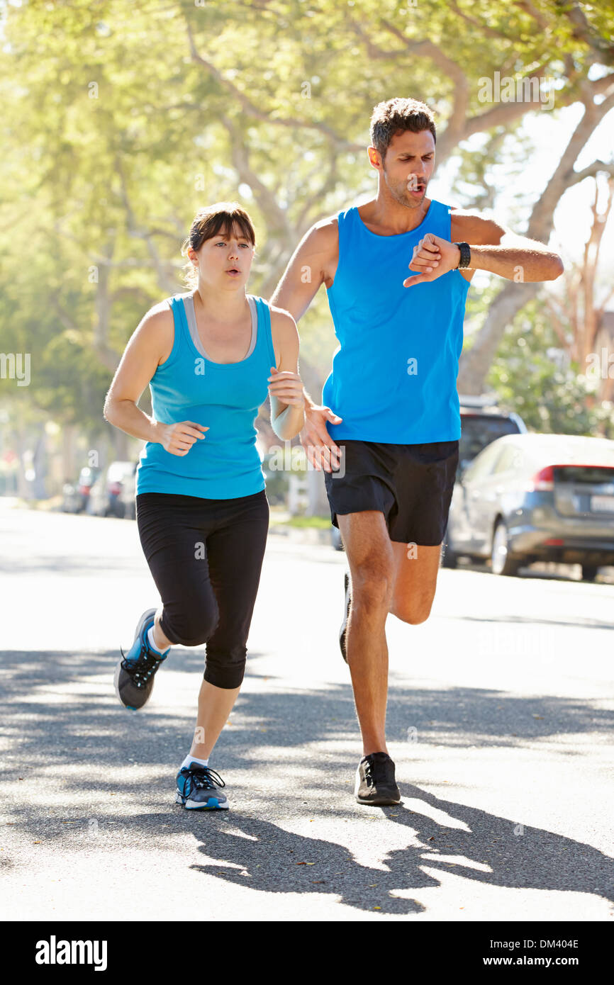 Woman Running Along Street With Personal Trainer Stock Photo
