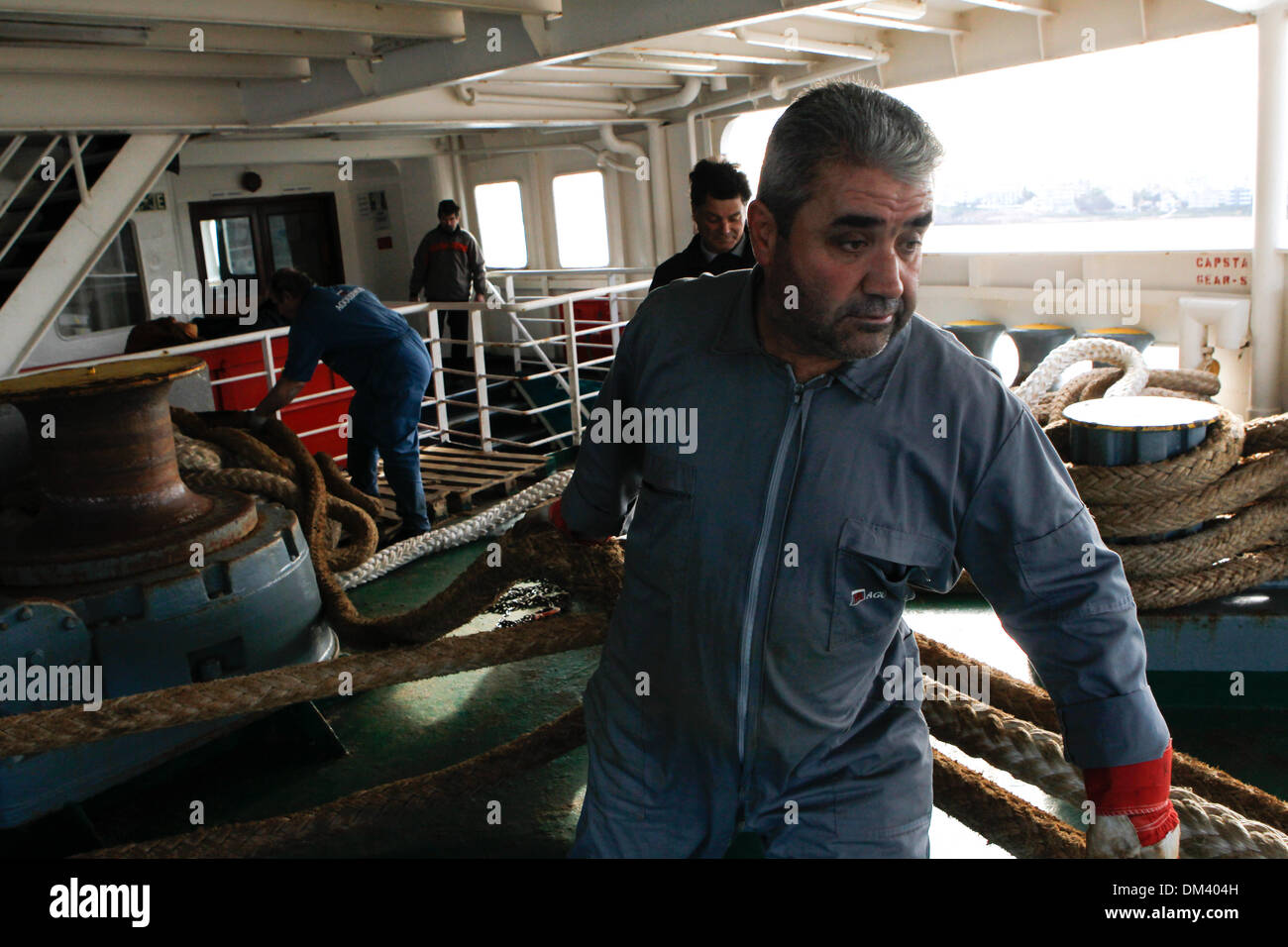 Ship crew guiding heavy duty mooring rope during docking procedure ...