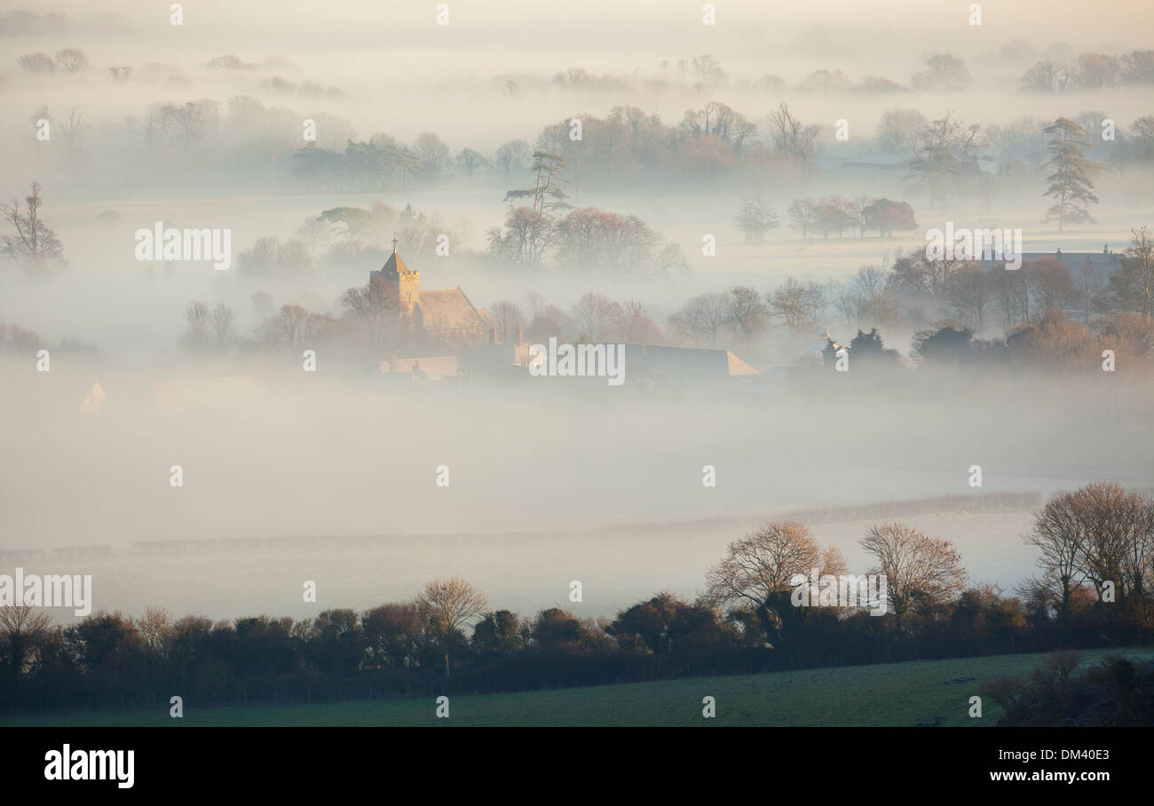 The village of Firle appearing through layers of mist on a winter's morning. Firle, East Sussex, England, UK Stock Photo