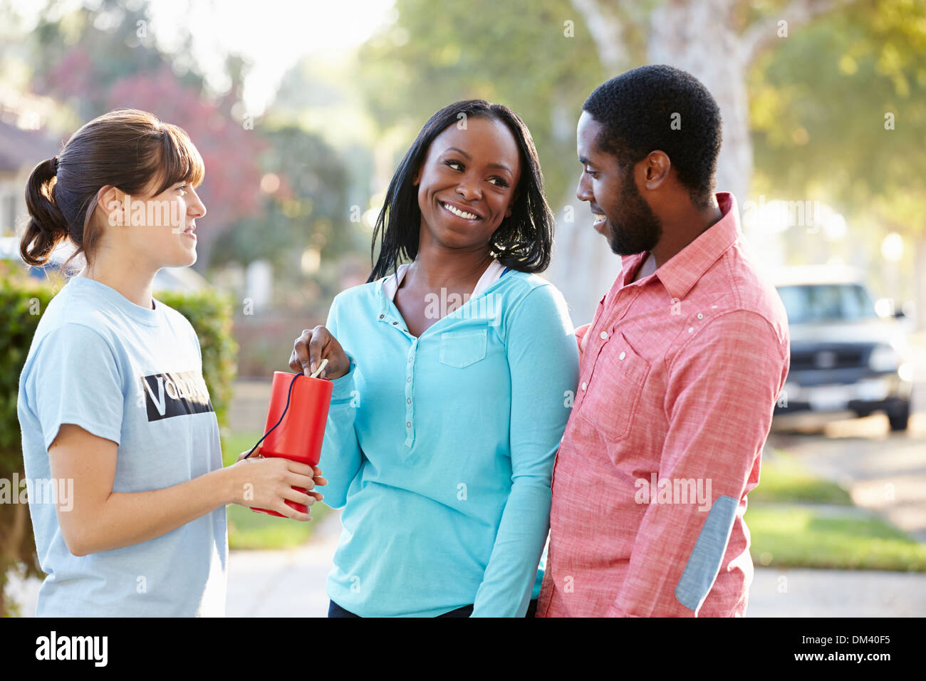 Charity Worker Collecting Sponsorship From Couple In Street Stock Photo