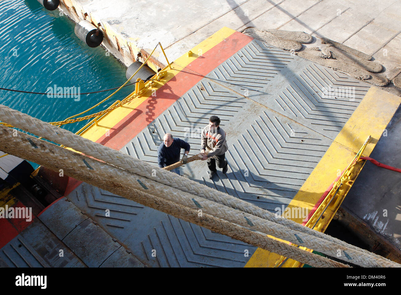 Ship crew guiding heavy duty mooring rope during docking procedure