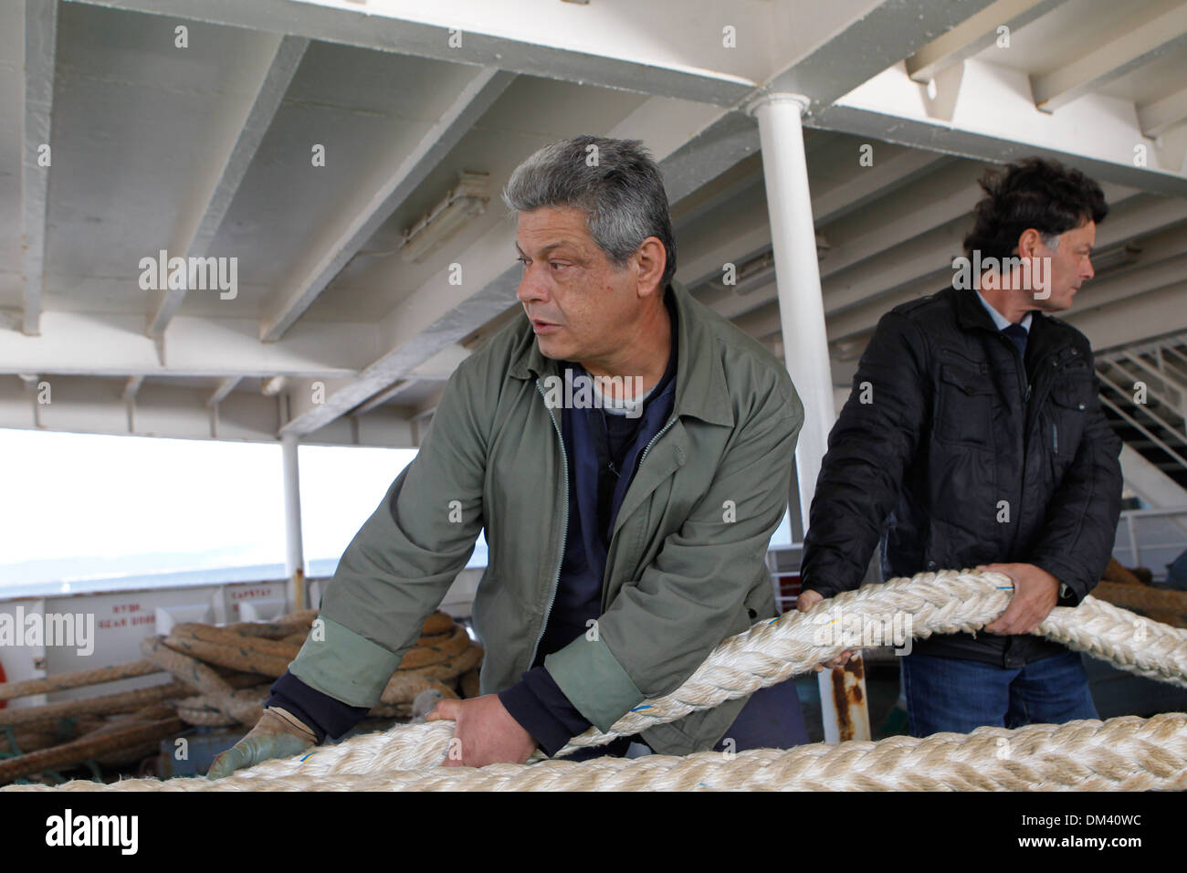 Ship crew guiding heavy duty mooring rope during docking procedure ...