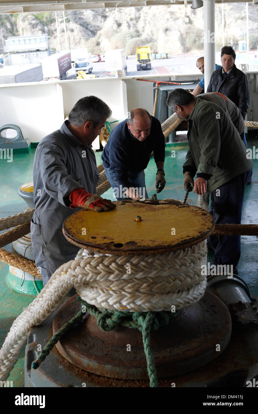 Ship crew guiding heavy duty mooring rope during docking procedure ...