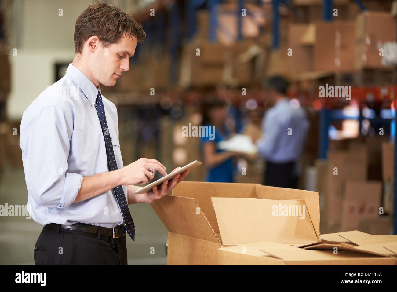 Manager In Warehouse Checking Boxes Using Digital Tablet Stock Photo