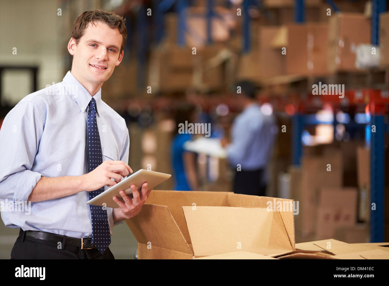 Manager In Warehouse Checking Boxes Using Digital Tablet Stock Photo